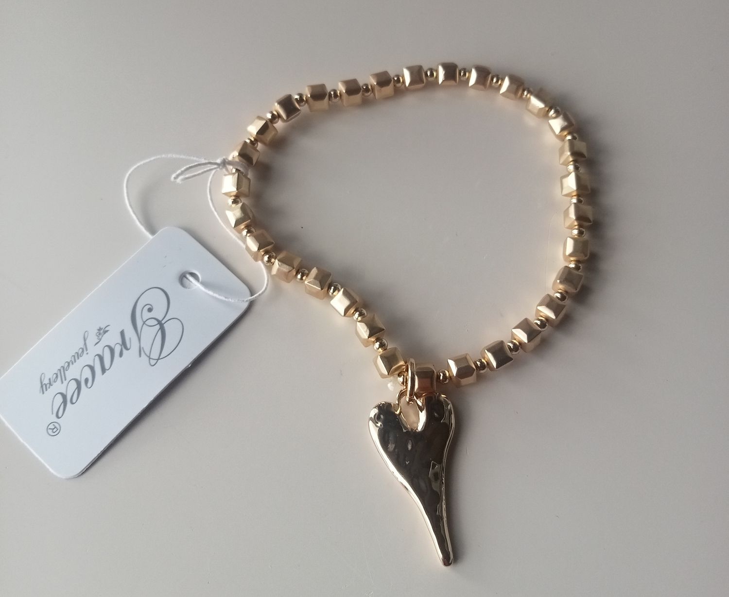 Elasticated bracelet with elongated heart in a gold tone.