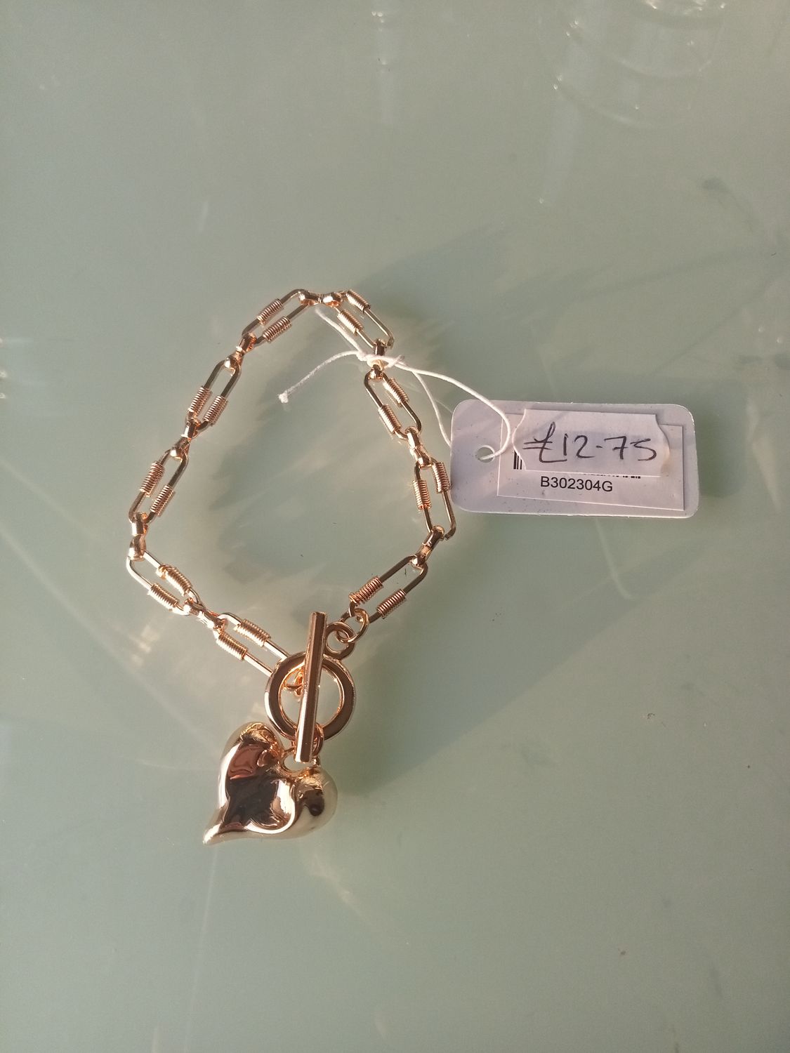 Gold tone paperclip chain bracelet with squashed heart. T Bar