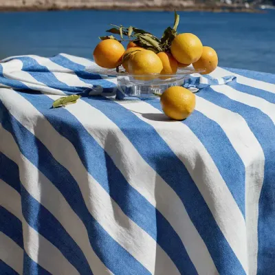 Rond blauw gestreept linnen tafelkleed op ronde tafel buiten gedekt in mediterrane sfeer