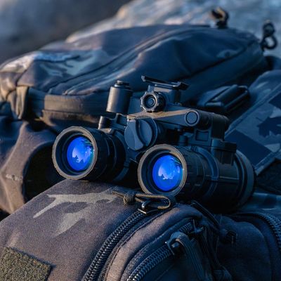 NVG‑ALPHA dual-tube night vision goggles with blue-filtered optics on tactical gear at sunset