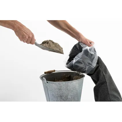 Ein Sandsack wird mit einer Schaufel über einem Eimer befüllt