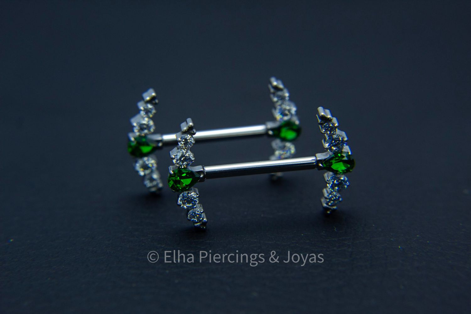 Barbell con secuencia de cristales de zirconia redondos y 1 cristal de zirconia central verde en forma de gota