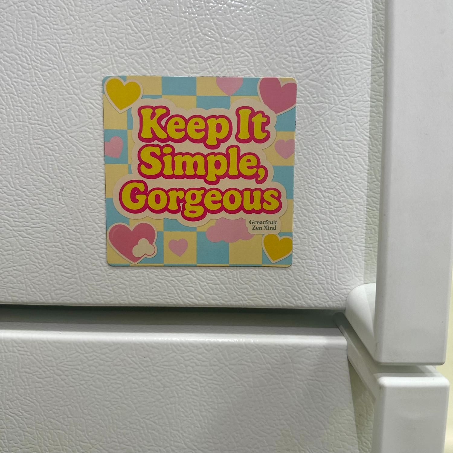 Large Magnet—Keep It Simple, Gorgeous Large ‘Keep It Simple, Gorgeous’ magnet with pastel checkered background and bold yellow stuck next to a refrigerator handle.