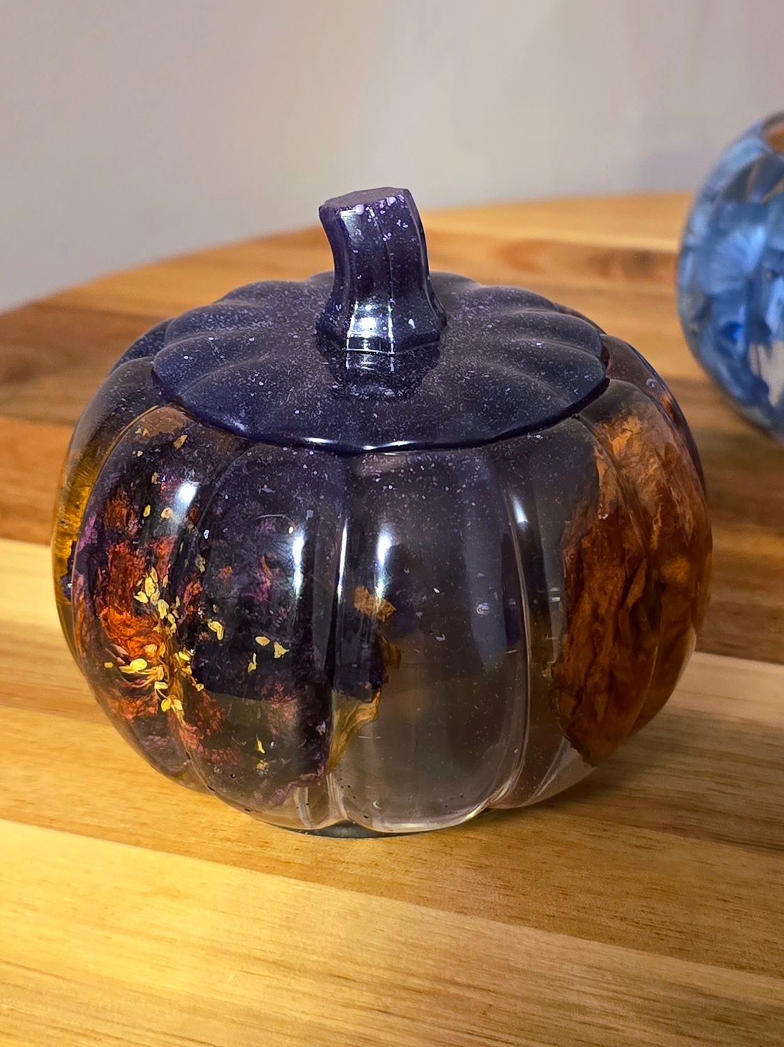 Epoxy resin purple pumpkin jar with dried flowers inside, glowing softly with fall ambiance.