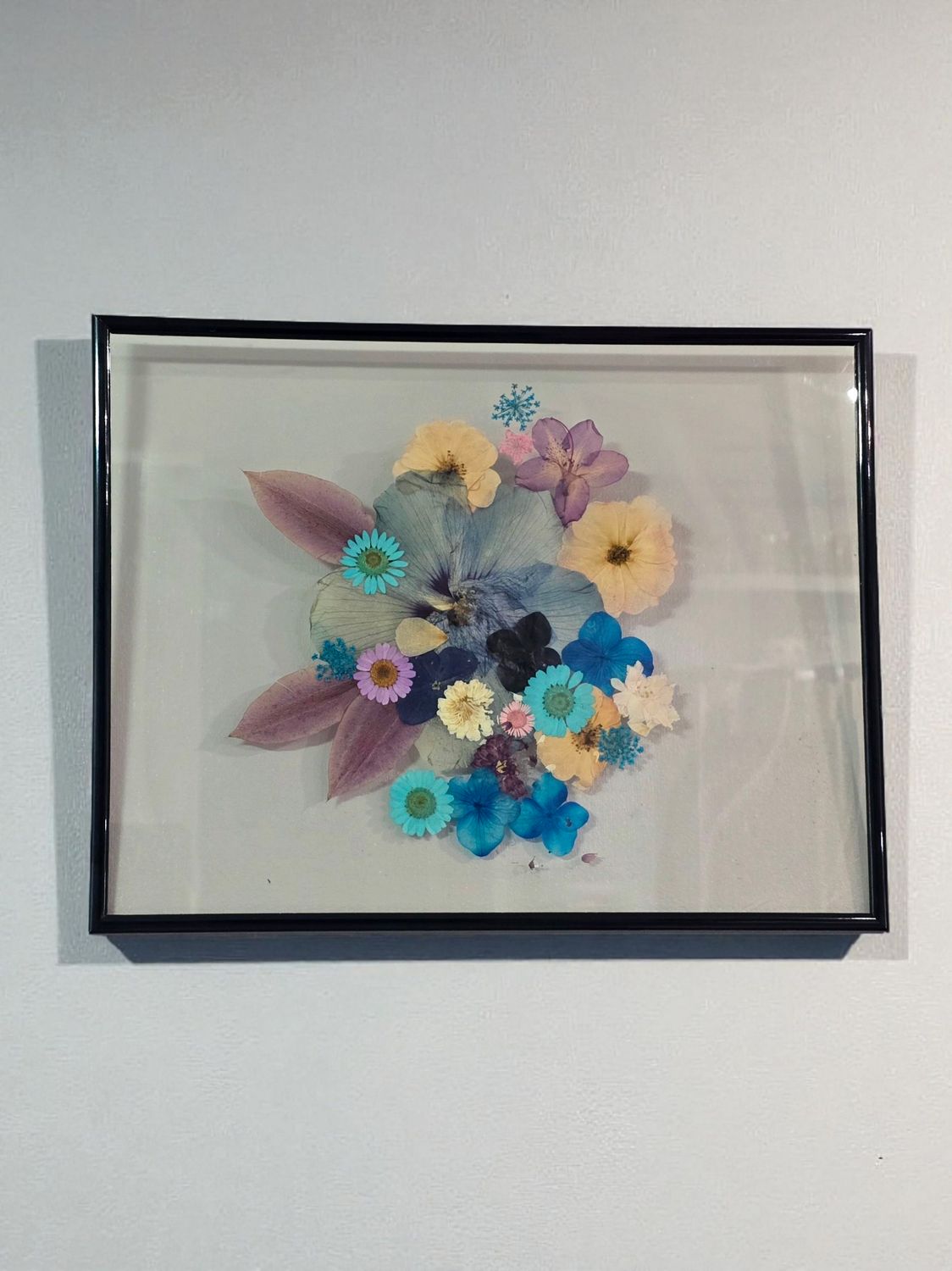 Pressed flower glass frame with colorful dried flowers in pink, yellow, blue, and lavender,