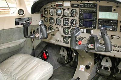 Cockpit van een licht sportvliegtuig met diverse cockpitaccessoires zoals kneeboard, headset, tablethouder en instrumentpanee