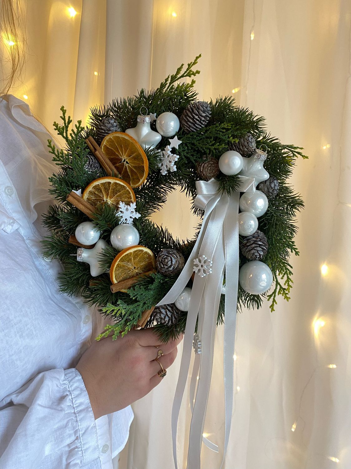 Świąteczny wianek na drzwi ze sztucznych gałązek – z suszonymi pomarańczami, białymi bombkami i gwiazdkami