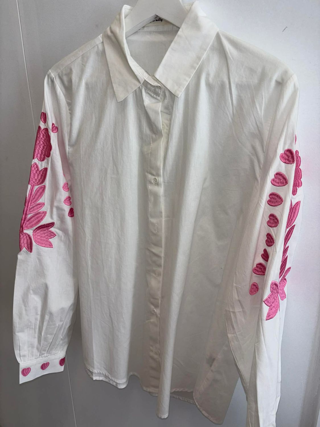Witte blouse met roze geborduurde hartjes.