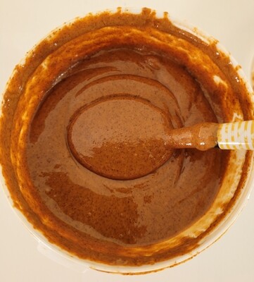 Close-up of creamy almond butter inside the tub with a spoon – showing thick, smooth texture and natural oils.