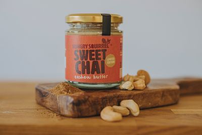 Sweet Chai Cashew Butter on a wooden board with scattered cashews – highlighting texture and core ingredients.


