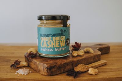 Jar of Sweet Cookie Dough Cashew Nut Butter with black lid and ingredients beside the jar. 