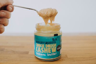 Spoonful of Cookie Dough Cashew Butter being lifted from the jar, showing its thick and gooey texture.