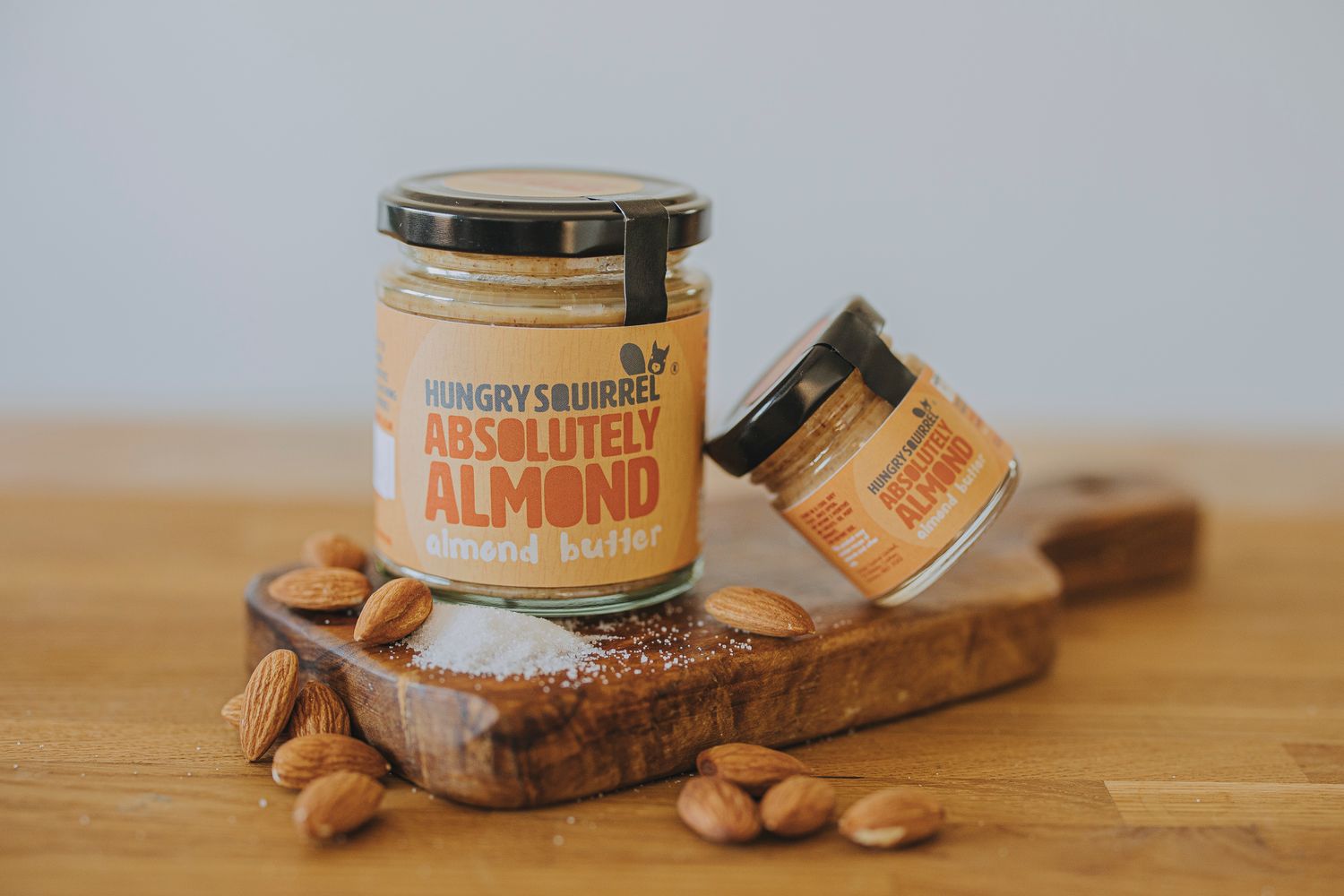 40g and 180g jars of Absolutely Almond Butter on a wooden board, surrounded by whole almonds.



