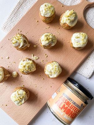 No-bake almond truffles rolled in chopped pistachios, with a mini jar of almond butter beside them.