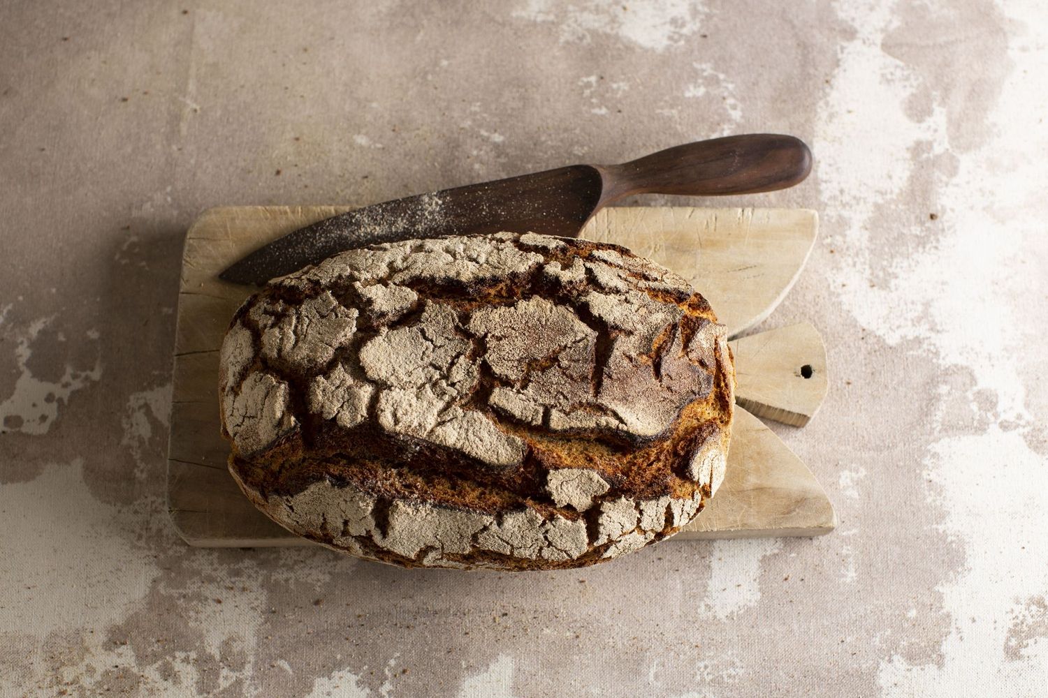 Nahaufnahme eines frisch gebackenen Brotes auf einem Holzbrett mit einem Brotmesser