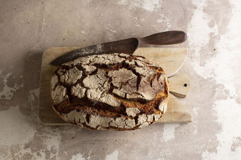 Nahaufnahme eines frisch gebackenen Brotes auf einem Holzbrett mit einem Brotmesser