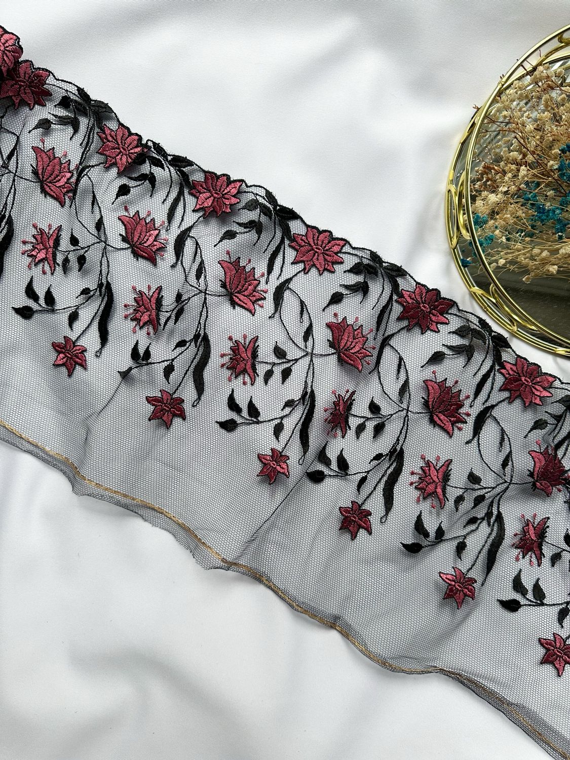 Encaje sobre tul negro con patrón floral rosa bordado
