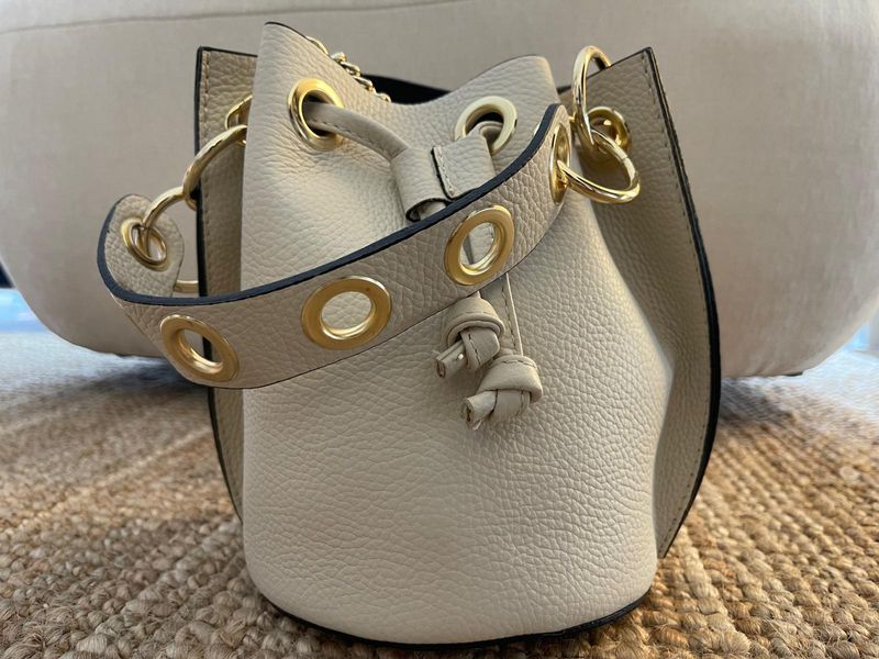 Bolso bucket de piel blanco roto con asa de mano y bandolera de cadena