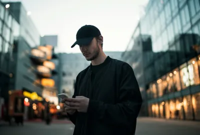 Man in baseball hat on a mobile phone trying to obtain ownership details for a UK mobile phone using Find UK People