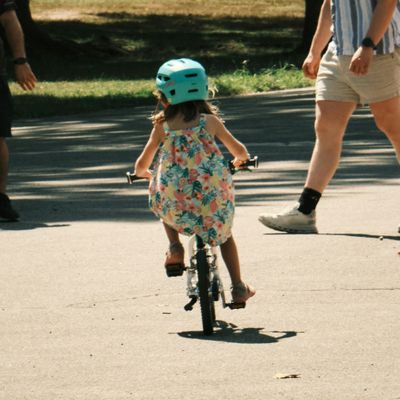 A child pedals her bike around a small concrete area