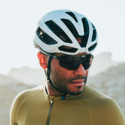 A man in cycling clothing looks off to the right to display the Kask Protone helmet that he is wearing