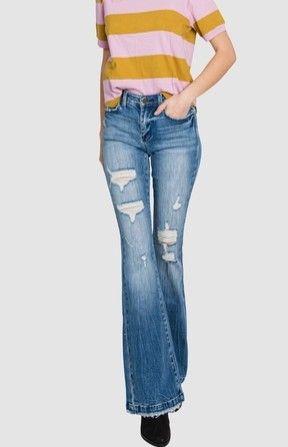 Model wearing blue destroyed mid-rise stretch flare jeans with knee distressing and a trouser hem.