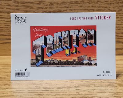 A red vinyl sticker that says 'Greetings from Trenton NJ' on it featuring a sunset and the Trenton skyline