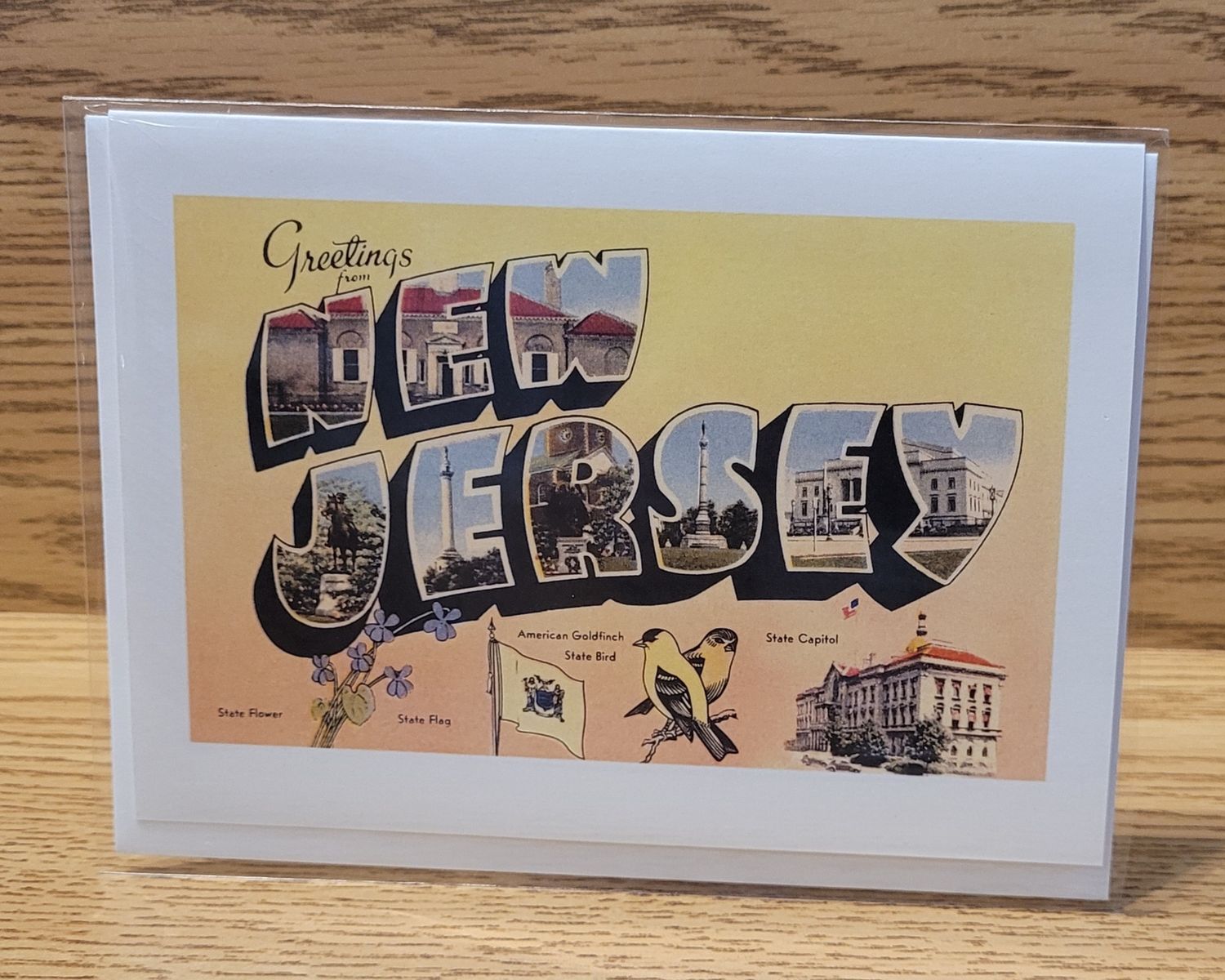 A greeting card that says 'Greetings from New Jersey' in a vintage style, with a yellow background, featuring state icons.