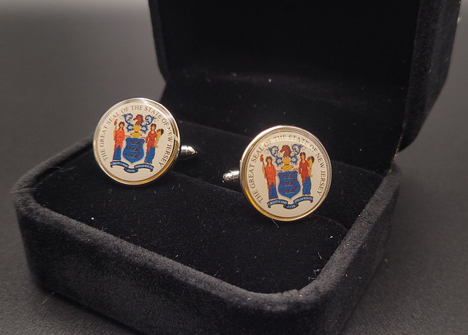 Two white cufflinks featuring the Great Seal of New Jersey in a black box