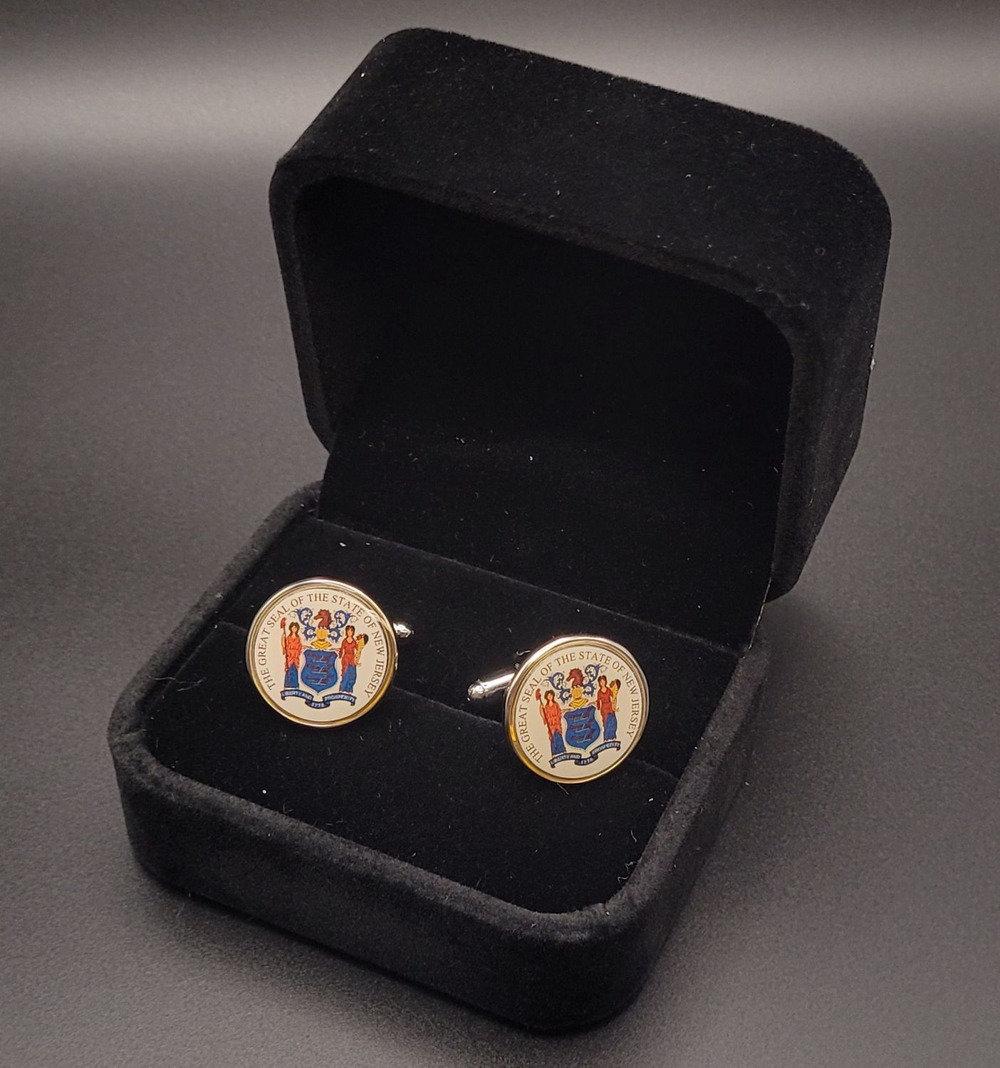 Two white cufflinks featuring the Great Seal of New Jersey in a black box