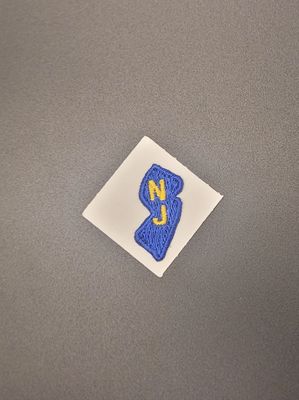 A blue patch with the letters N and J on it in the shape of New Jersey.