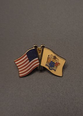 A lapel pin featuring an American Flag on the left and the New Jersey flag on the right.
