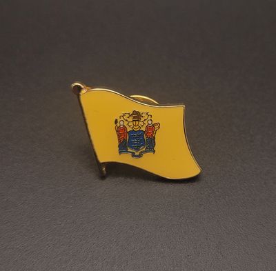 A yellow lapel pin of the flag of New Jersey with the Great Seal in the middle of it.