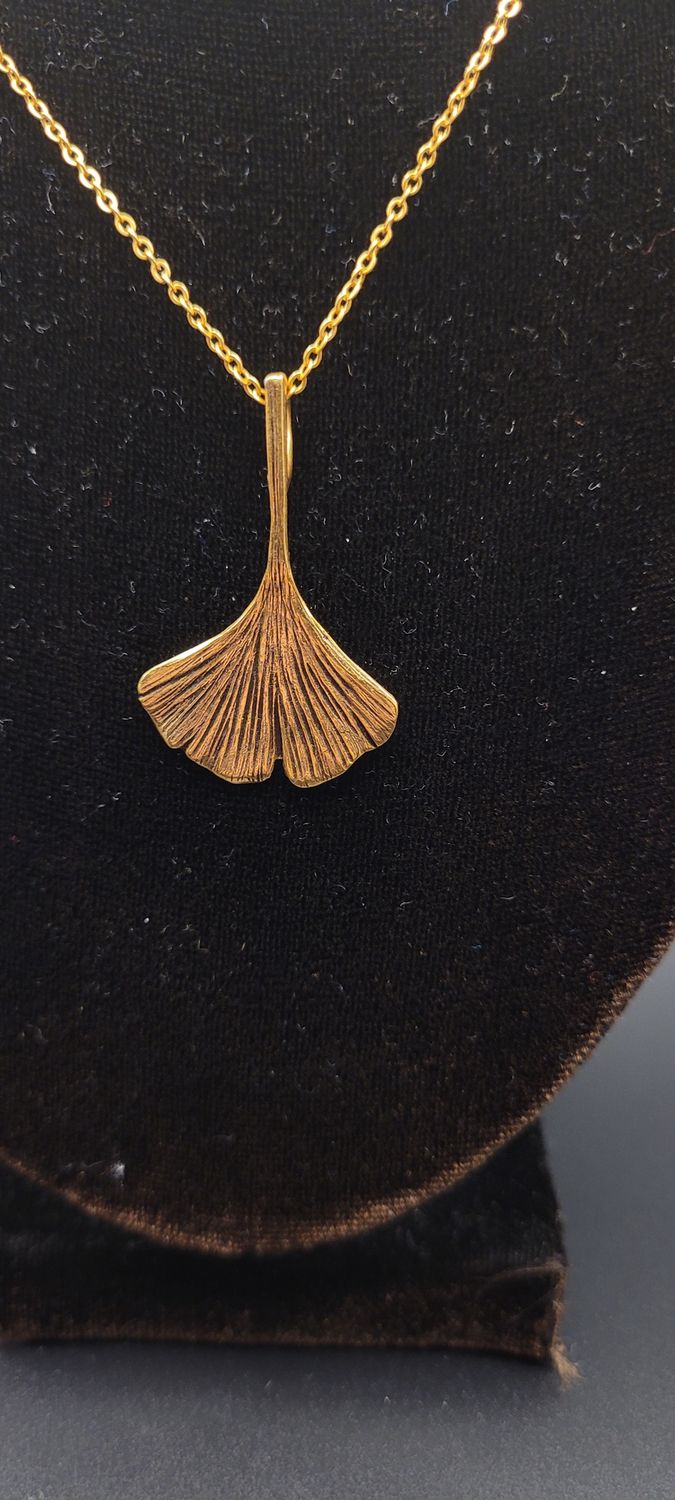 A close-up image of a gold metallic ginkgo leaf pendant.