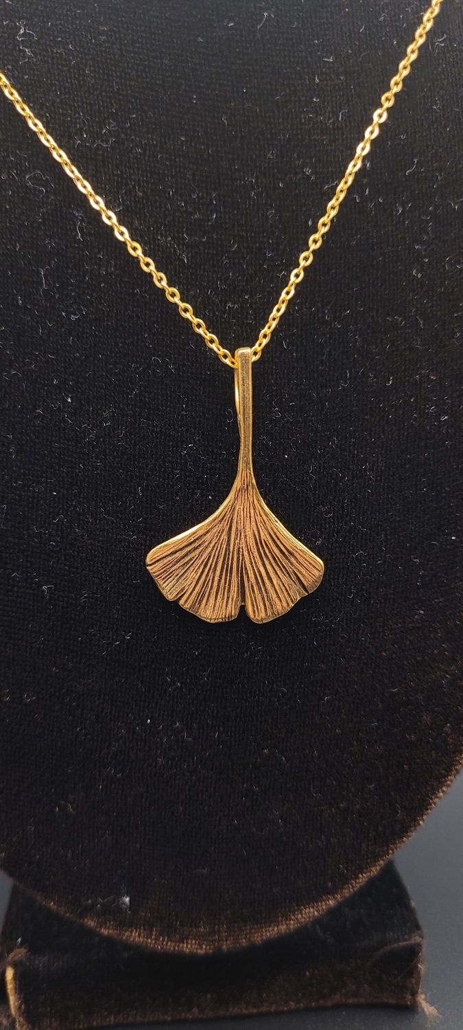 A close-up image of a gold metallic ginkgo leaf pendant.