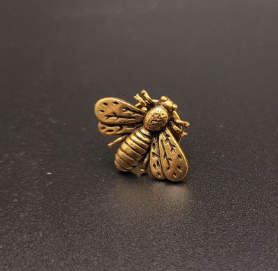 A lapel pin featuring a metallic bee.