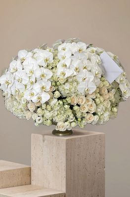 White roses, spray roses, lisianthus, hydrangeas and orchids in a gold pedestal vase – Pearl Elegance by J.T.Fleurs