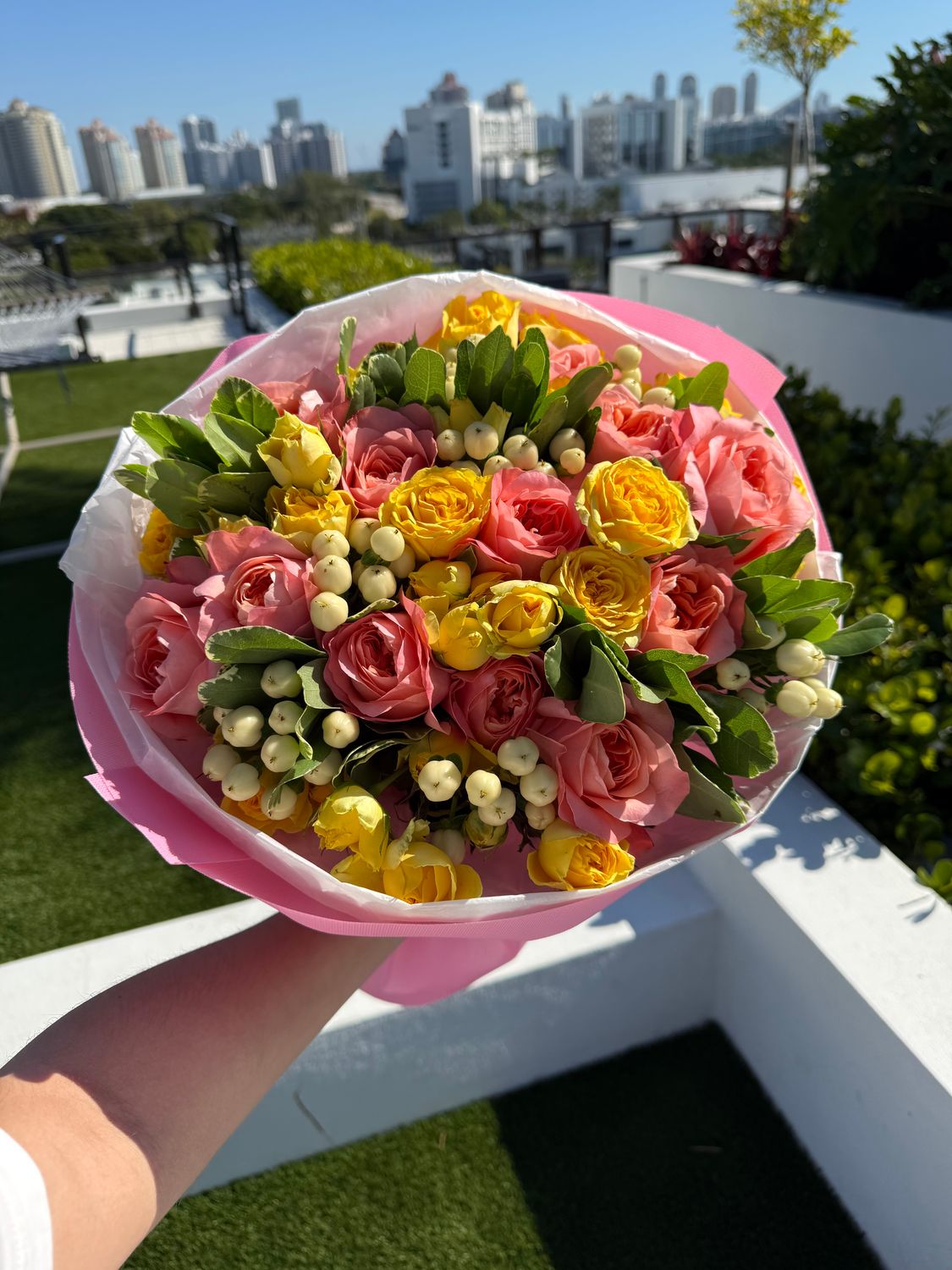 Bouquet with pink single roses, yellow spray roses, hypericum and pittosporum in pastel wrapping – Je T’aime Fleurs Miami 