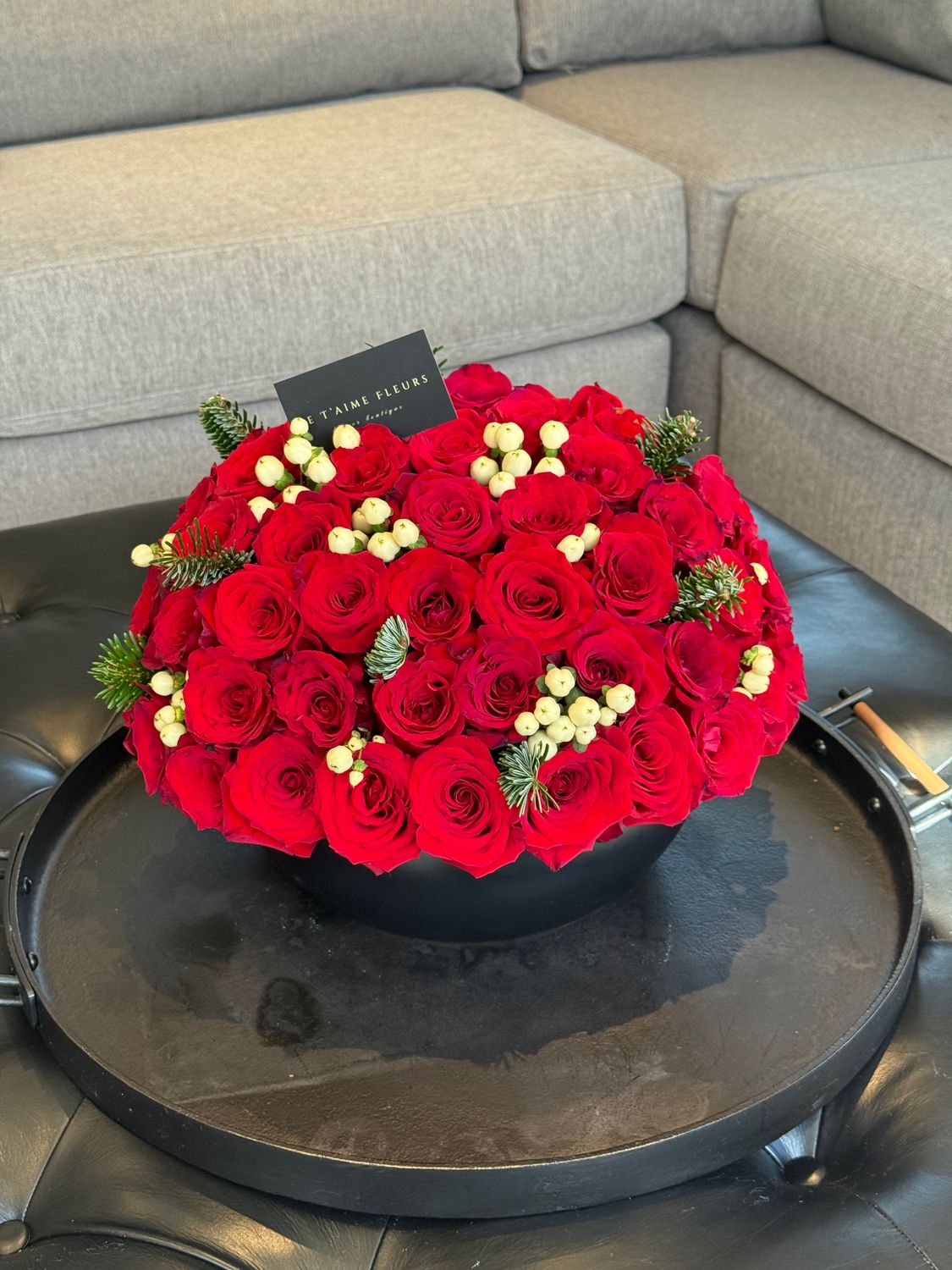 Lush red rose winter centerpiece with white hypericum and evergreen accents in a black vase – Je T’aime Fleurs Miami &amp; Naples