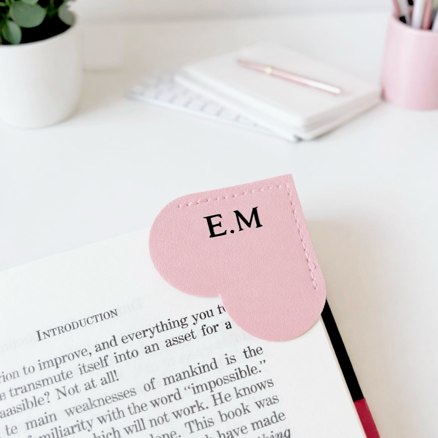 Personalised pink heart shaped bookmark with initials in a book