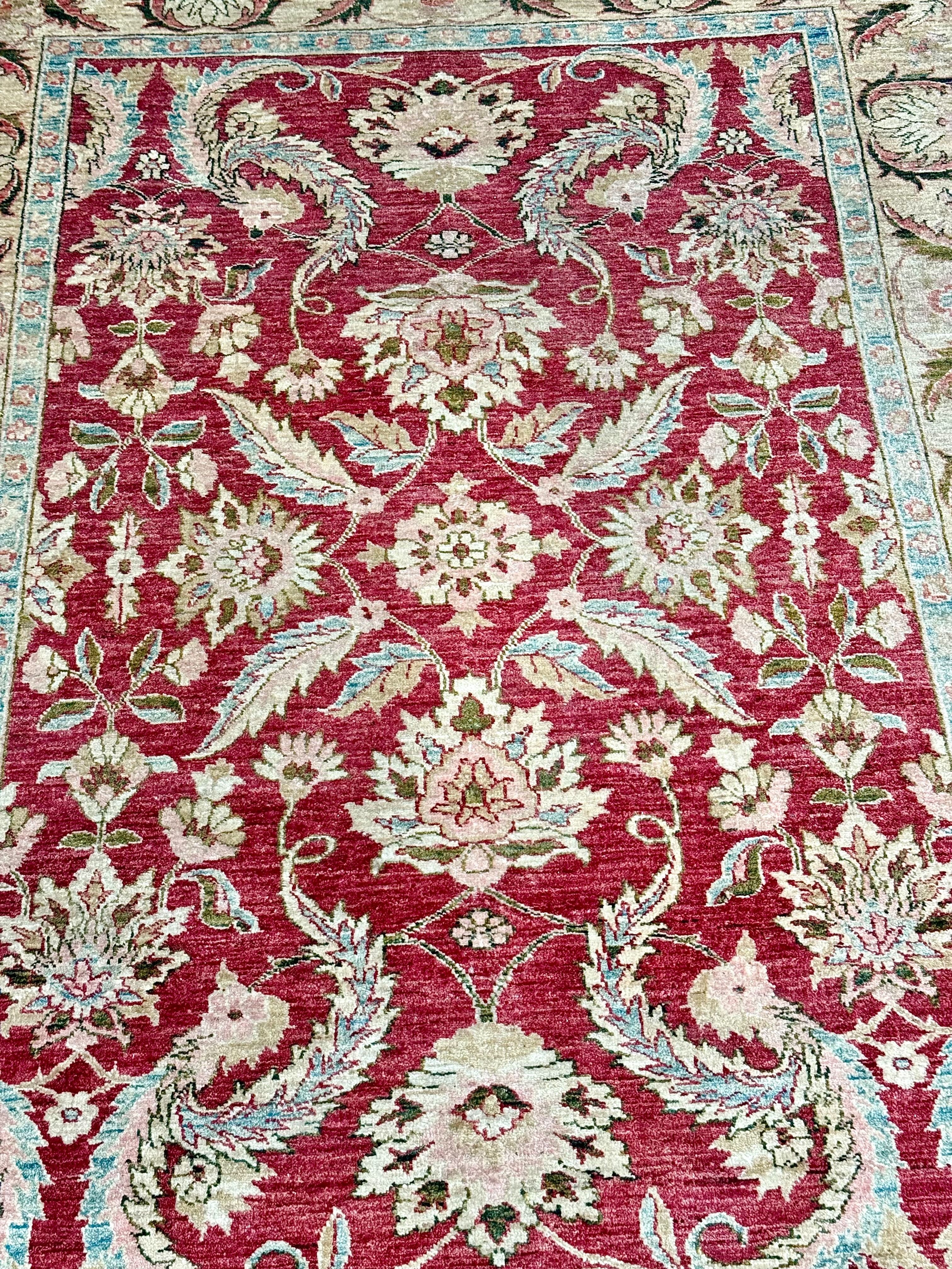 Tapis persan en laine noué à la main avec fond rouge et bordure florale