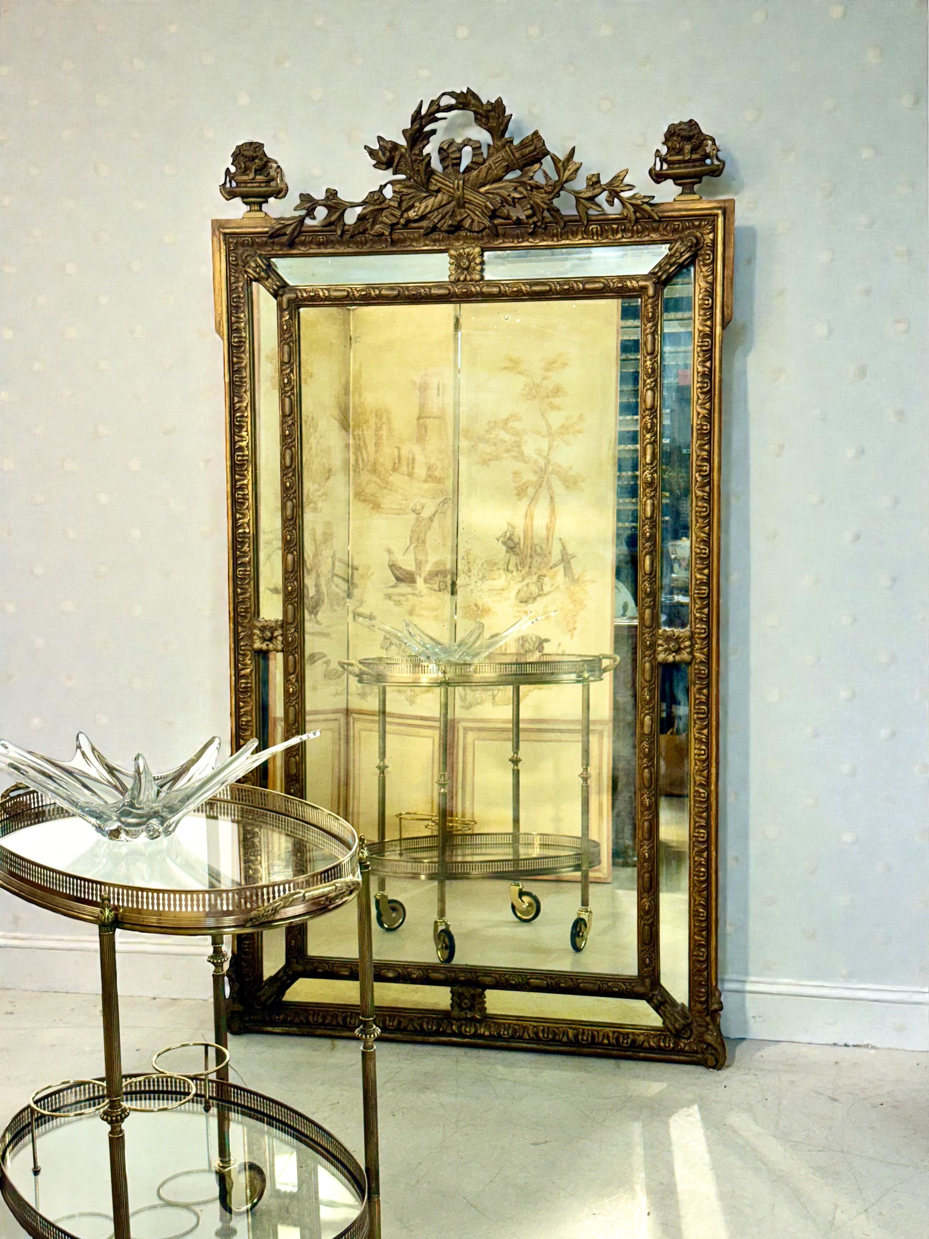 Grand miroir Napoléon III en bois doré orné d'une crête de laurier et de glace vieillie