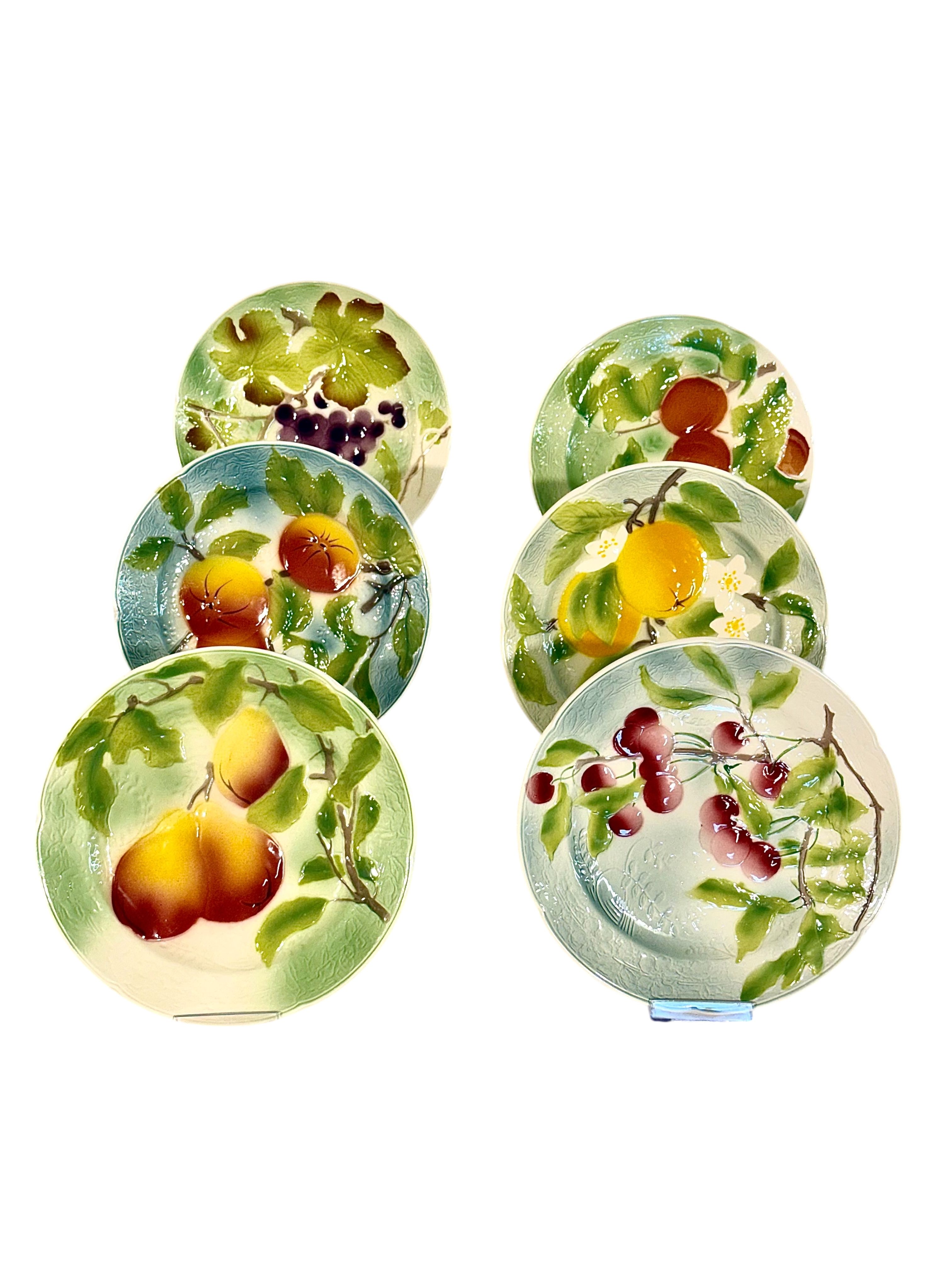 Suite de six assiettes à dessert aux fruits en barbotine de Saint Clément, vers 1900