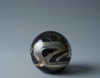 Vintage Mdina glass paperweight in zwart glas met zilverachtige swirl, frontaanzicht