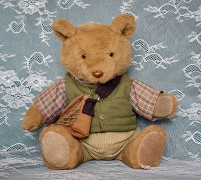 Voorkant Bo‑Bear Designs teddybeer met groene bodywarmer, geruite blouse en licht verkleurde corduroy broek