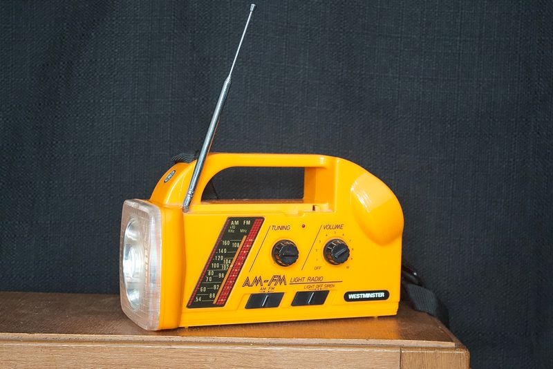 Vintage oranje Westminster noodradio met lamp, draagriem en antenne