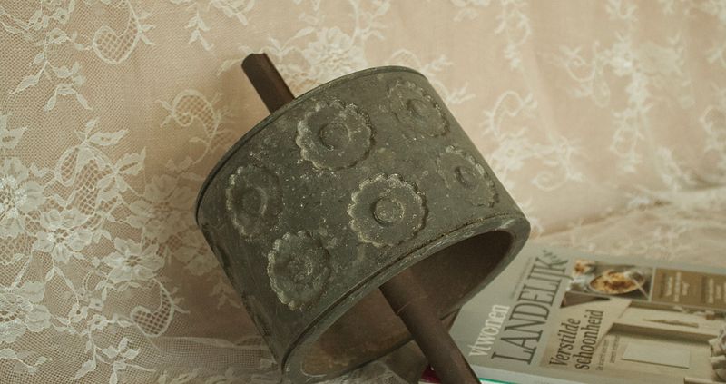 Sfeerafbeelding van de antieke deegroller, die de rozetpatronen en as laat zien, met een tijdschrift