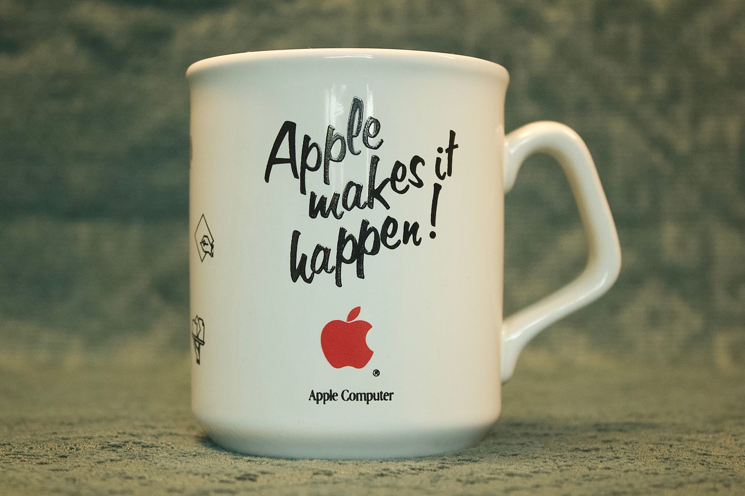 Zijaanzicht van de vintage witte Apple-mok, met de slogan 'Apple makes it happen!' in zwart schrift en een rood Apple-logo