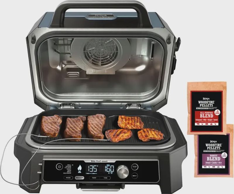 Ninja Woodfire ProConnect Premium XL Outdoor Grill &amp; Smoker with the lid open, cooking meat inside.