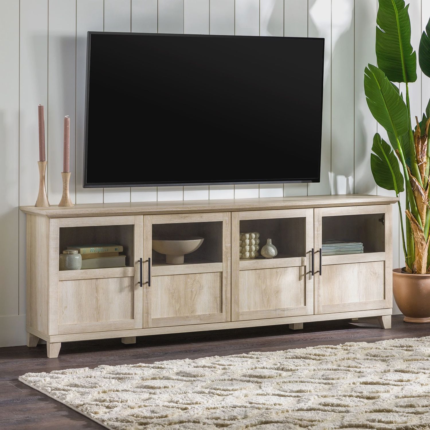 Walker Edison Farmhouse TV Stand Cabinet in white oak with a large flat-screen TV on top, styled in a cozy living room.